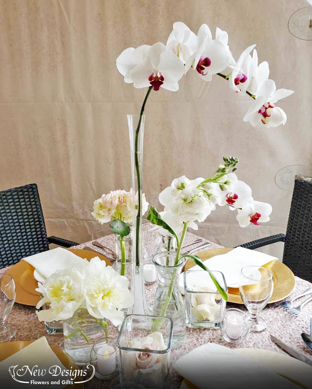 A centerpiece in various styles and heights of vases, each featuring a single bloom alternating between a nude rose, white peony, tall white Phalaenopsis orchids and hydrangea